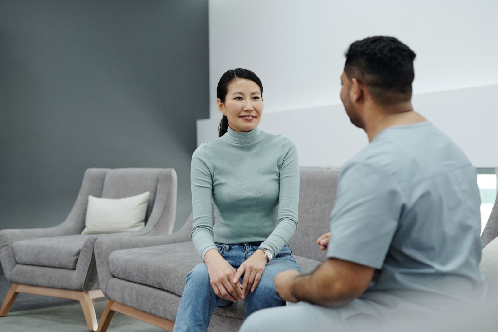 A woman in a green sweater talks with a healthcare provider in a modern office