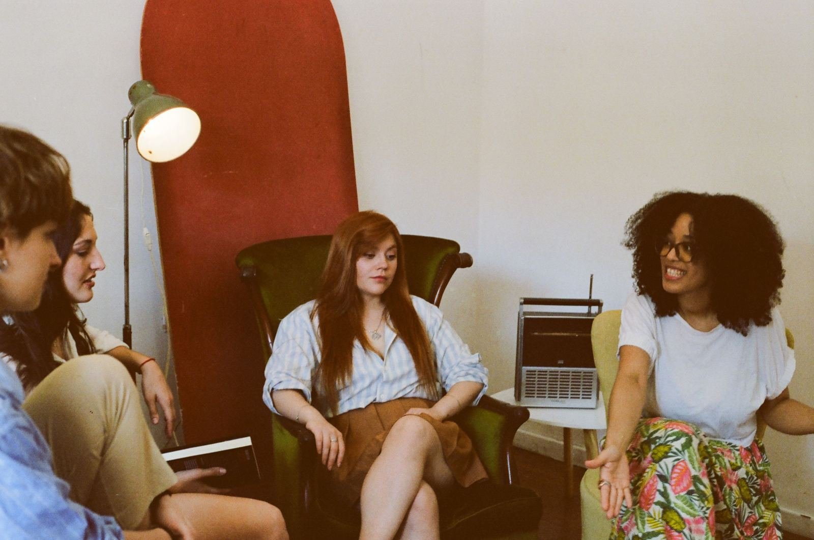 Three women talk in a circle in a bright room