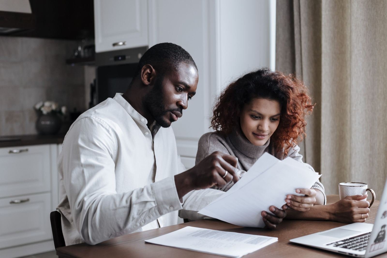 A couple sits at a kitchen table looking over papers