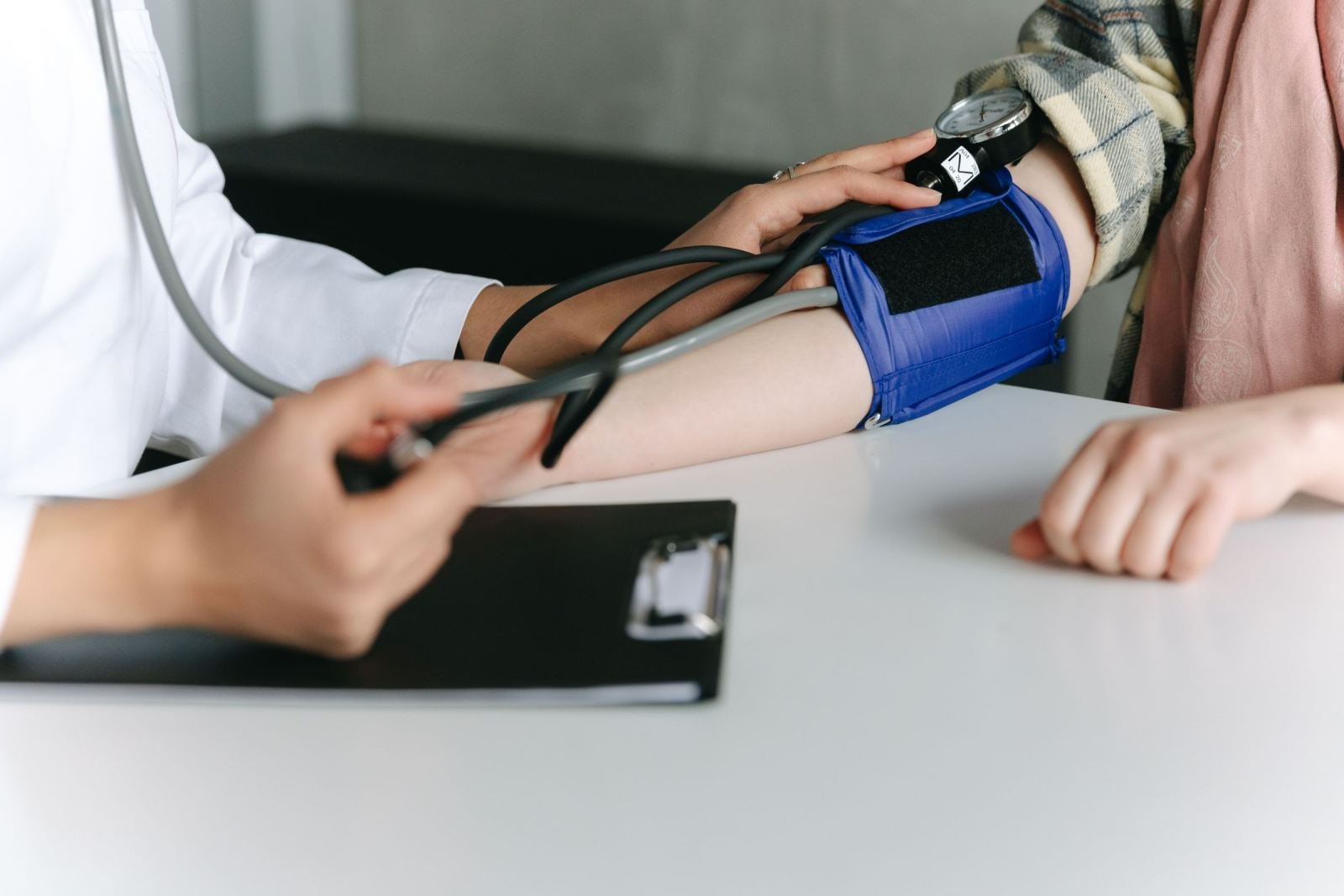 A healthcare provider takes a patient's blood pressure with a manual cuff