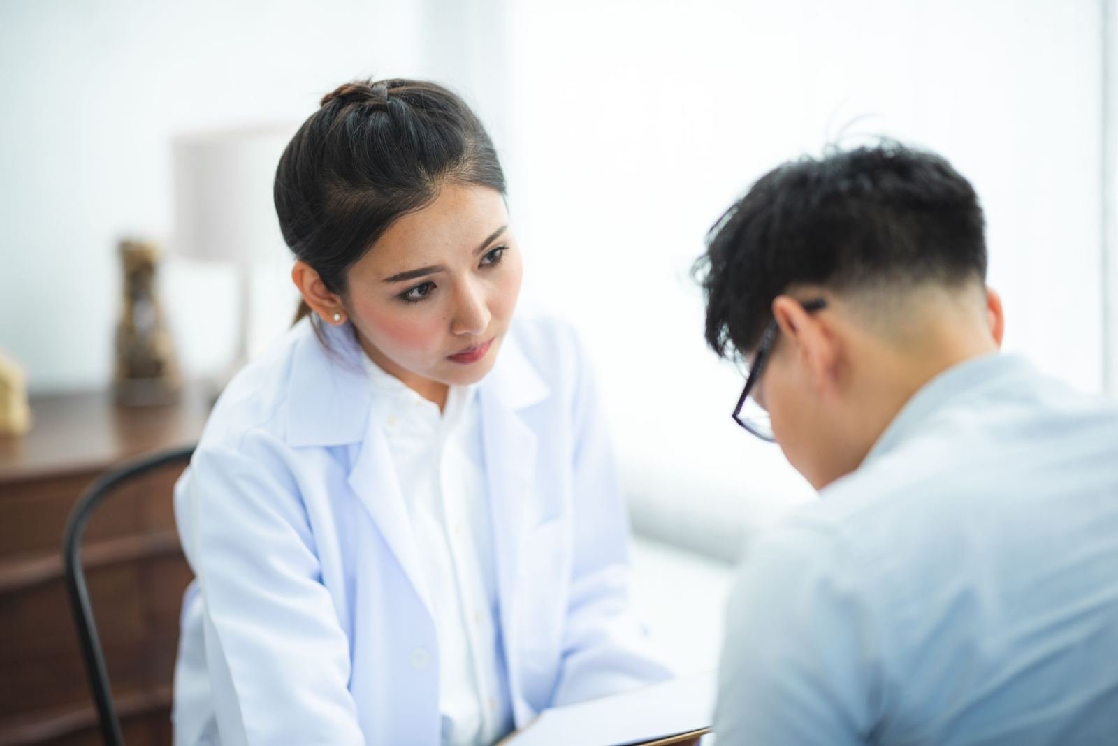 A doctor in a white coat listens to a patient in a medical office