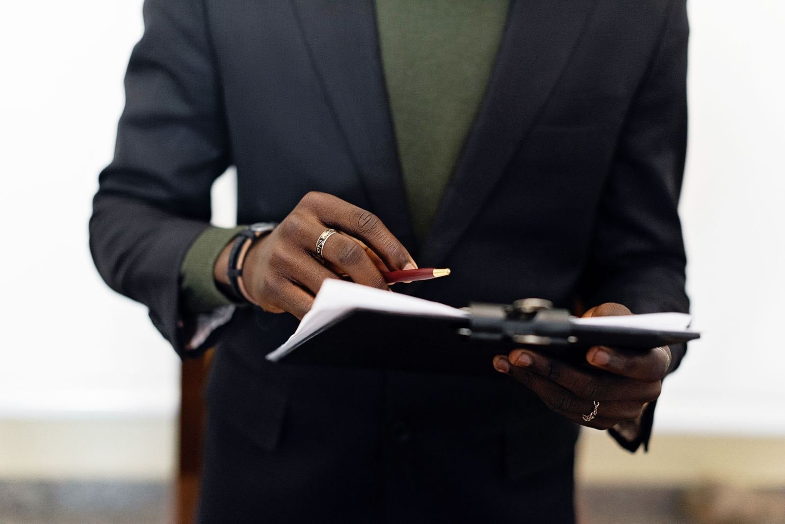 A person in a suit holding a clipboard and pencil