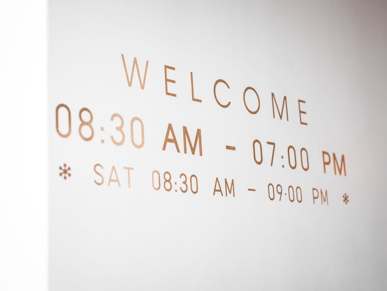 Business hours and a welcome message printed on a white wall