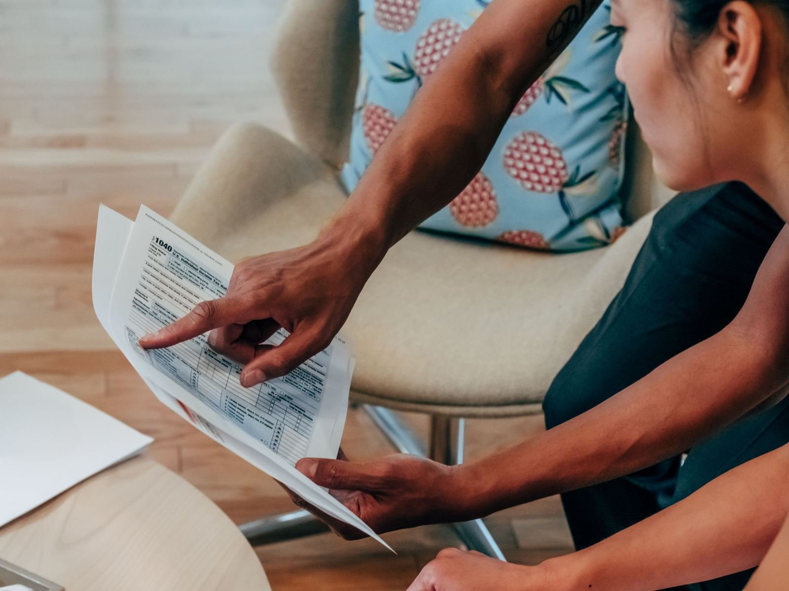 A person pointing to a line on a tax form while sitting in a chair
