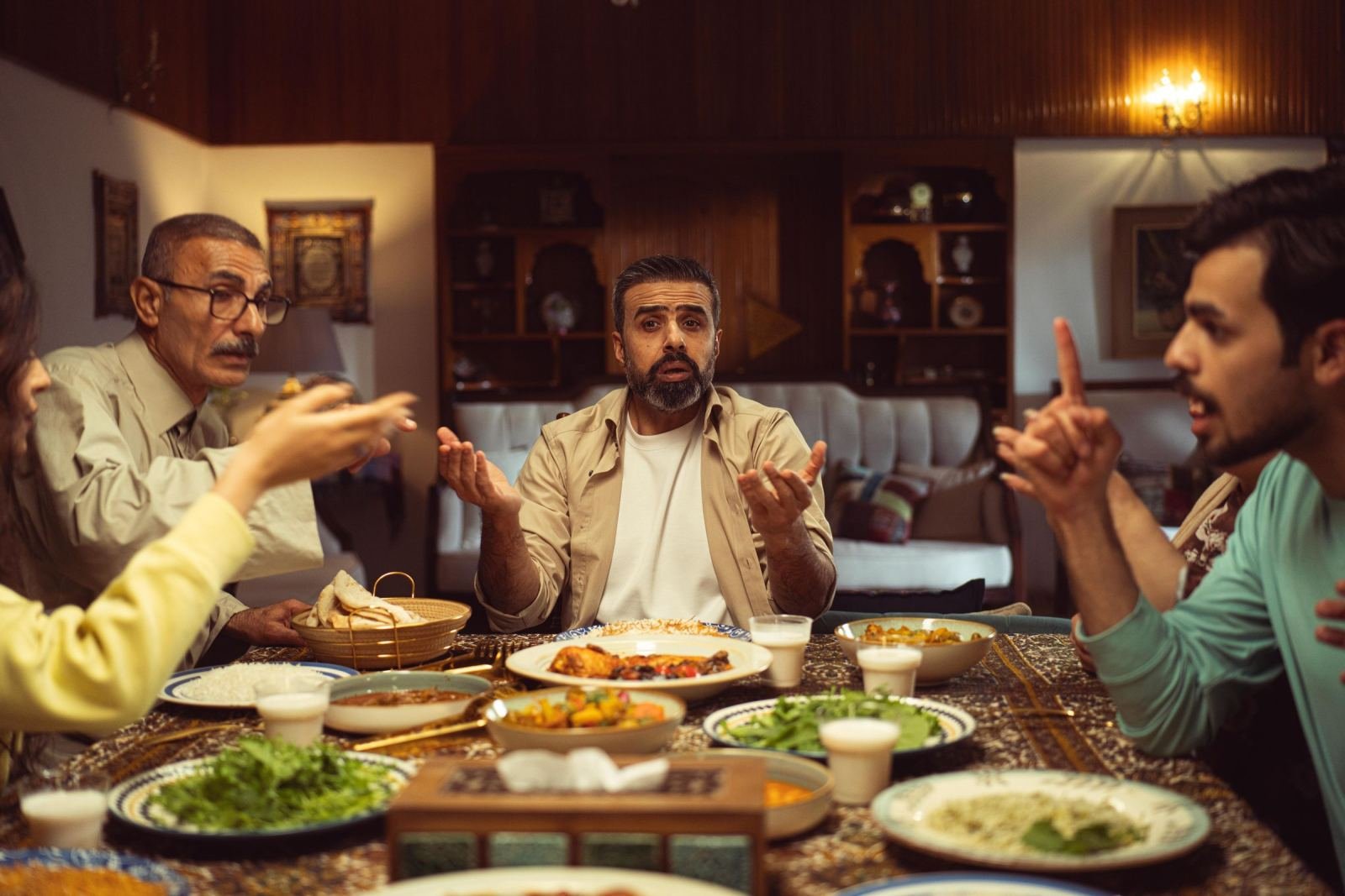 Four people having an intense conversation around a dinner table with food