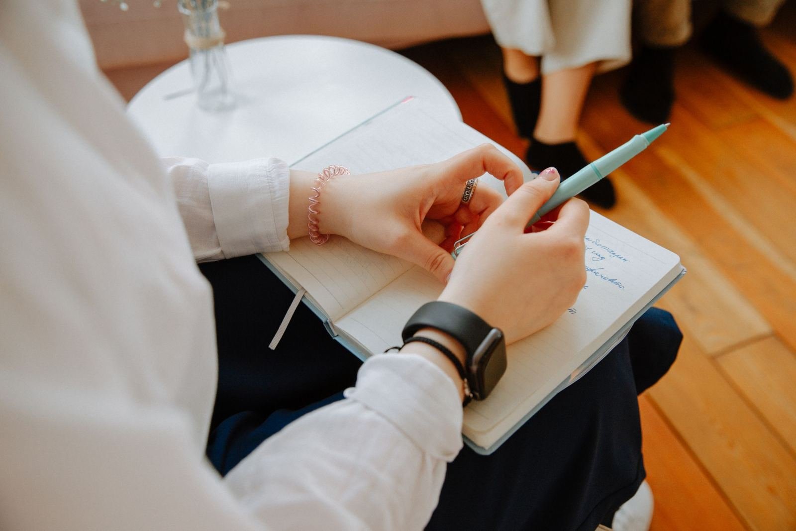 Someone writes in a journal with a blue pen during a session.