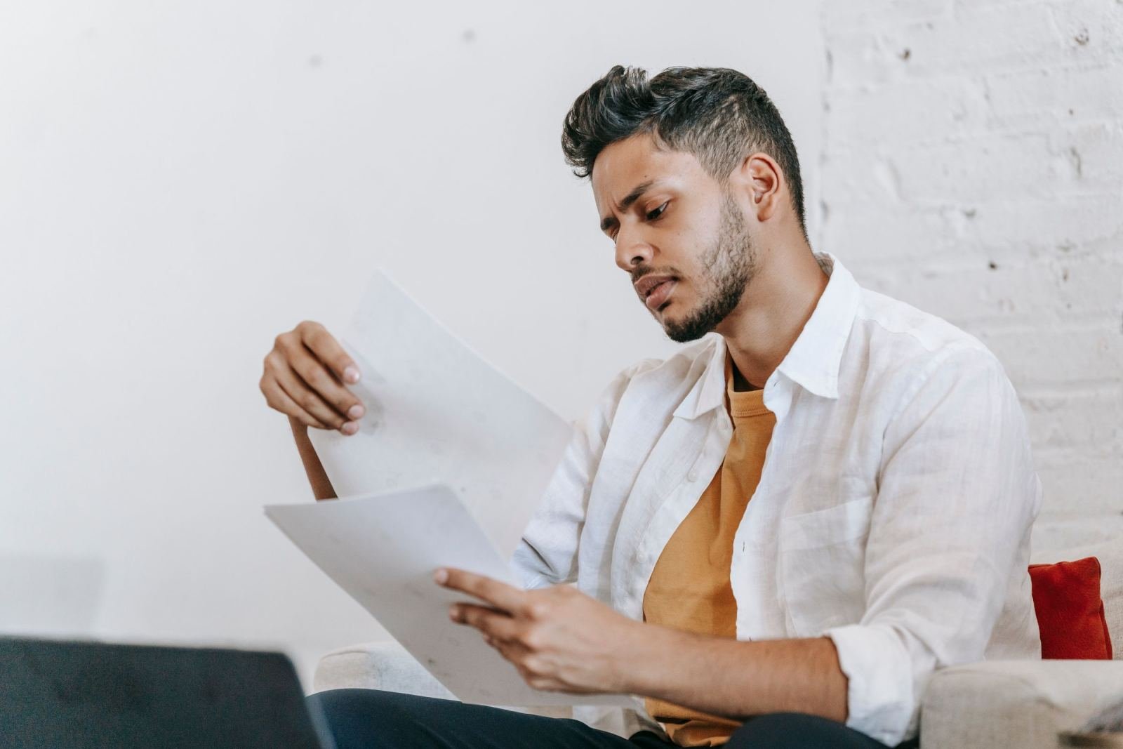 A man in a white shirt reviews papers while sitting in a bright room