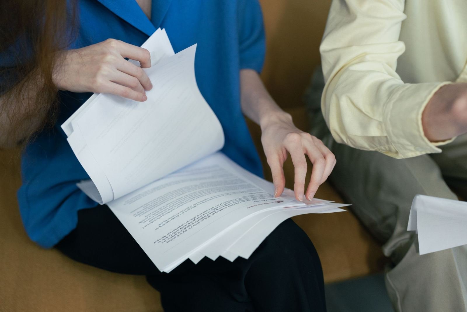Two people sitting together reviewing a stack of application papers