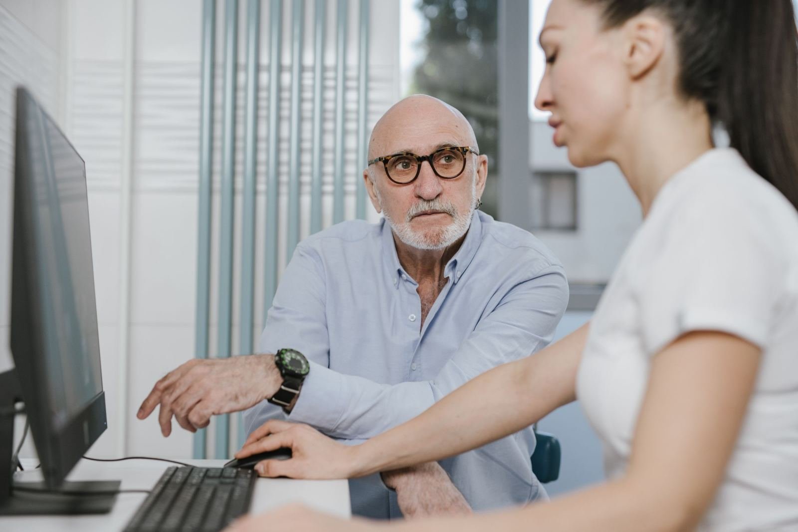 A clinician and a patient look at a computer screen together in an office