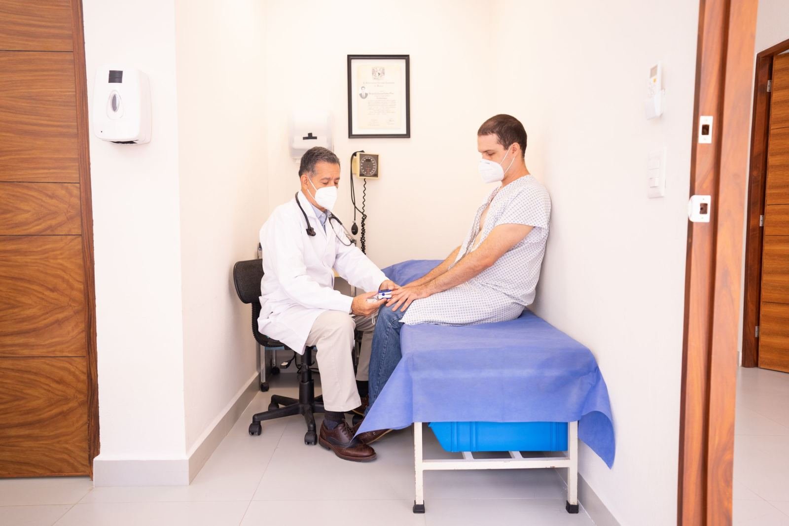 A doctor in a white coat checks a patient's finger with a pulse oximeter
