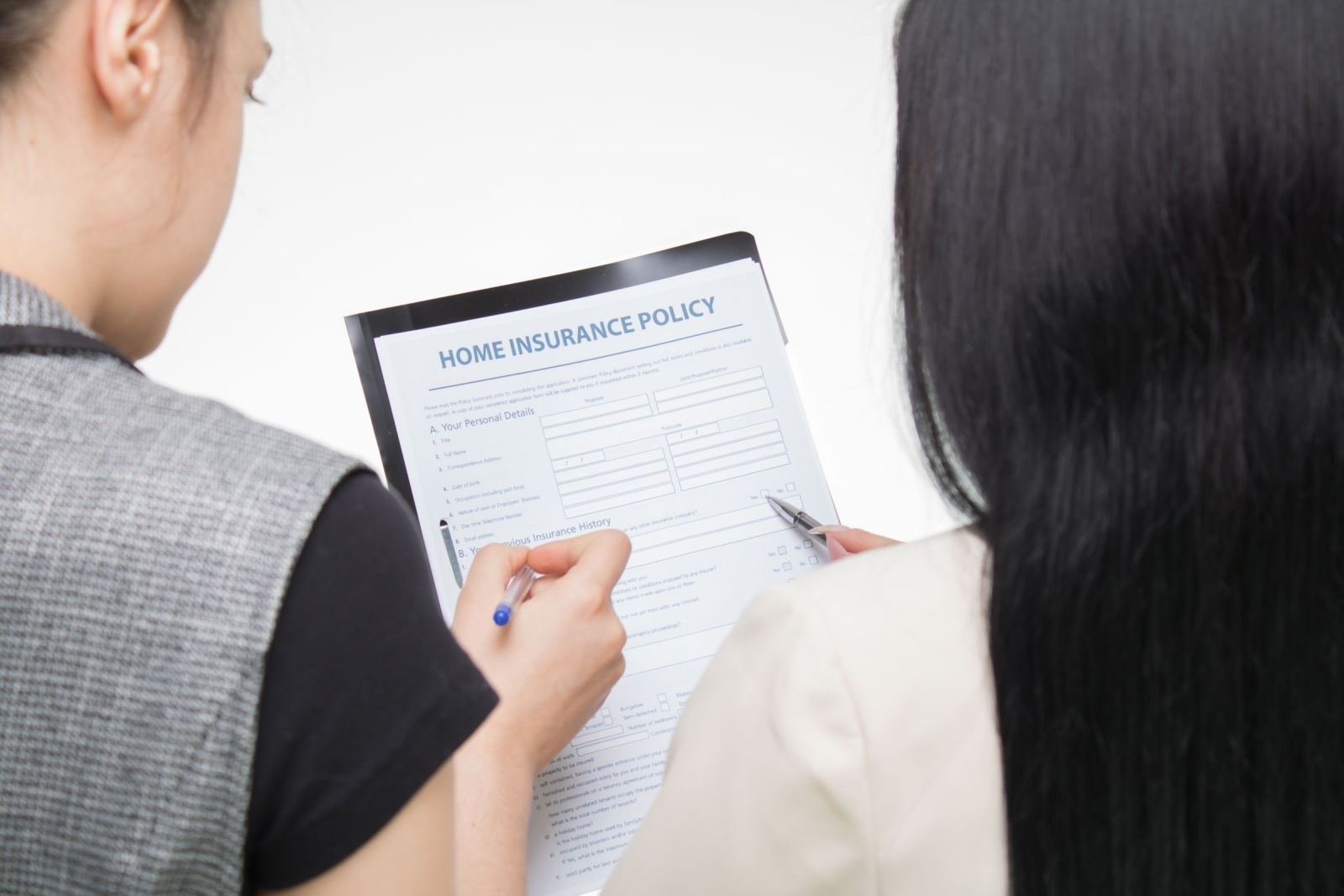 Two women review a home insurance policy document on a clipboard