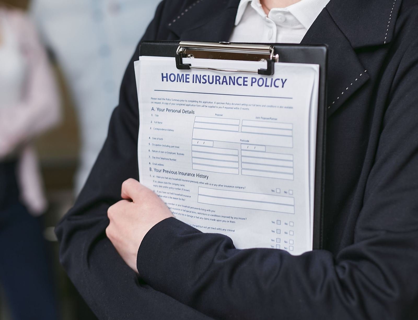 A person in a blazer holds a clipboard with an insurance policy document