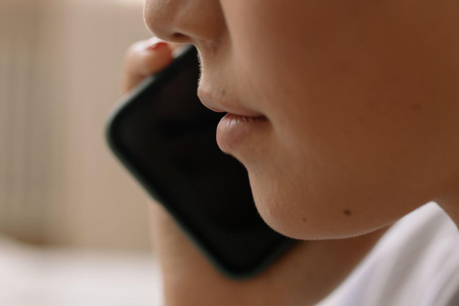 A person holds a smartphone close while speaking.
