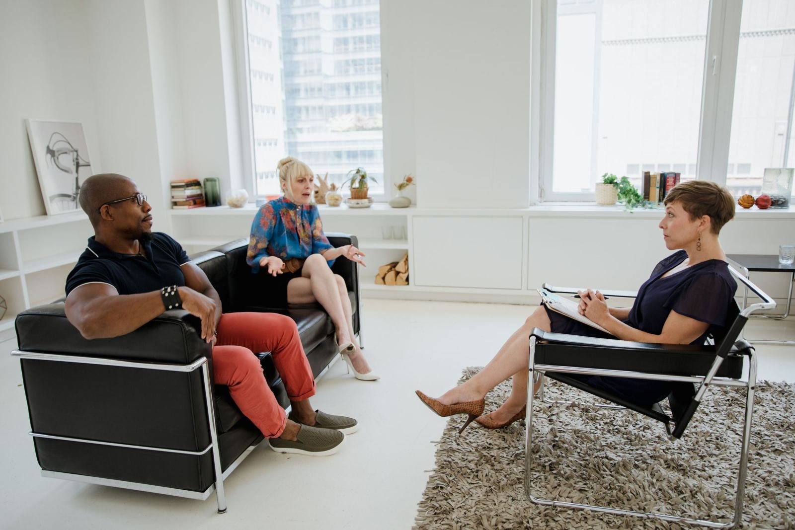 A counselor with a clipboard talks with a man and woman in a bright office