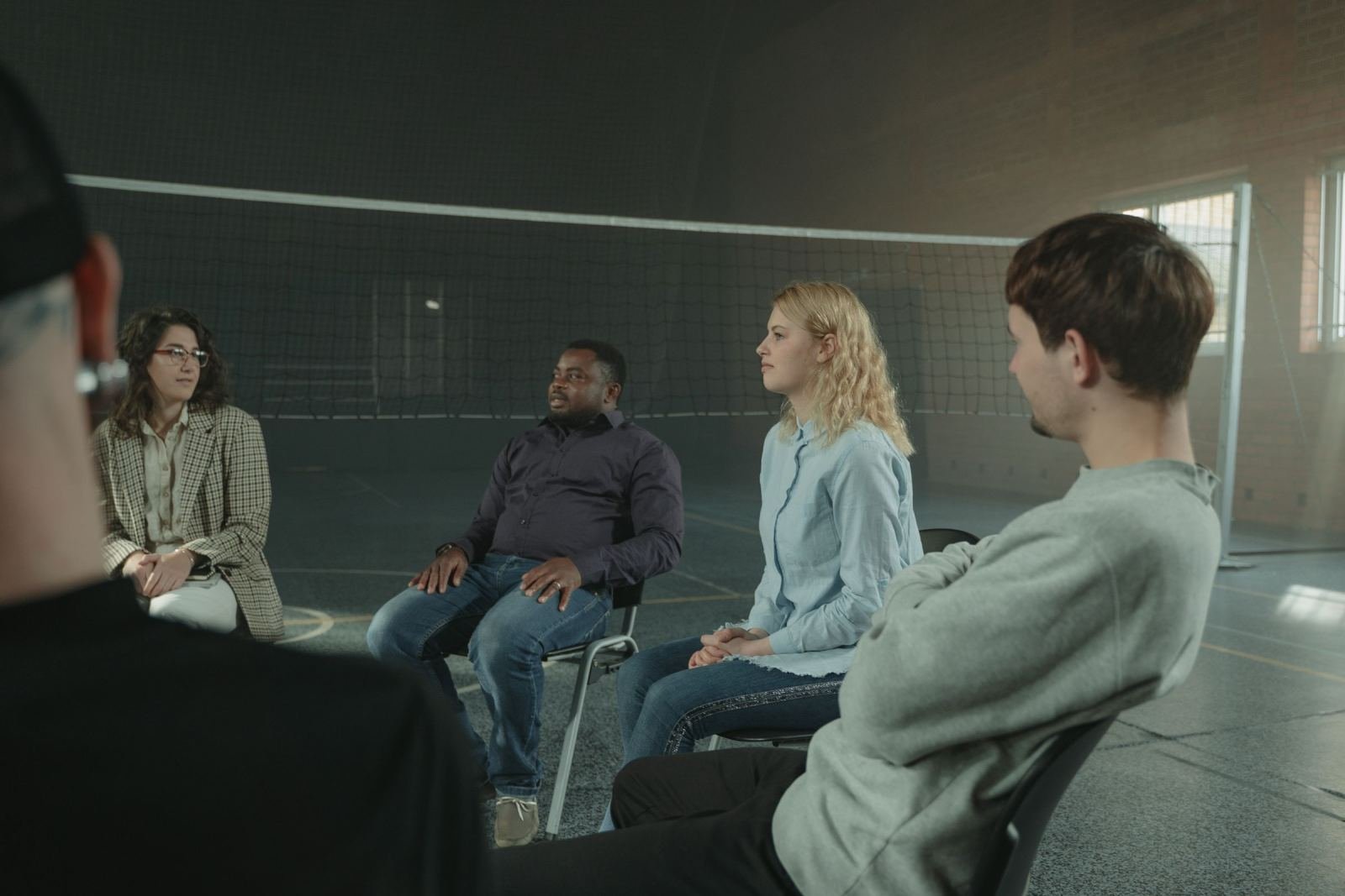 Four people sit in a circle of chairs for a group discussion in a large indoor space