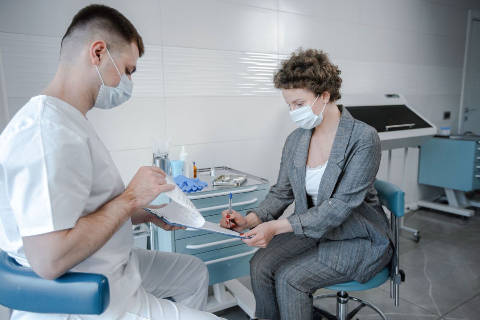 A doctor and a patient wearing face masks review a document together in a clinic