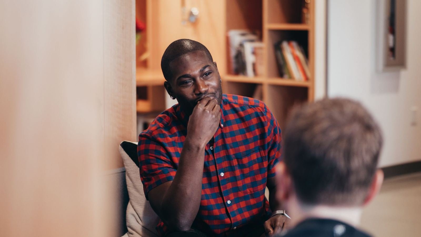 A man in a plaid shirt talks with a professional in a bright room