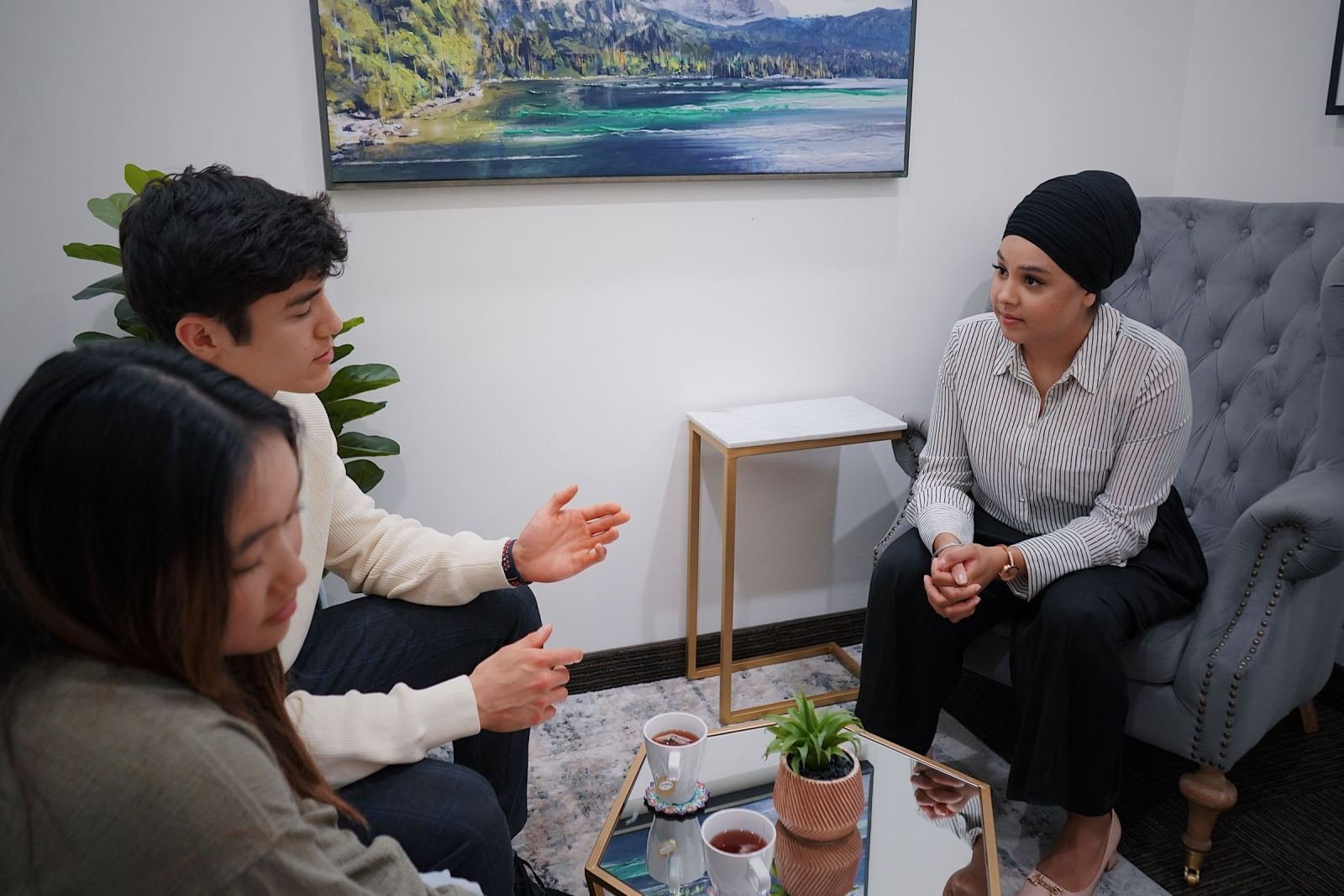 A woman in a turban listens to a man and woman in a professional office setting