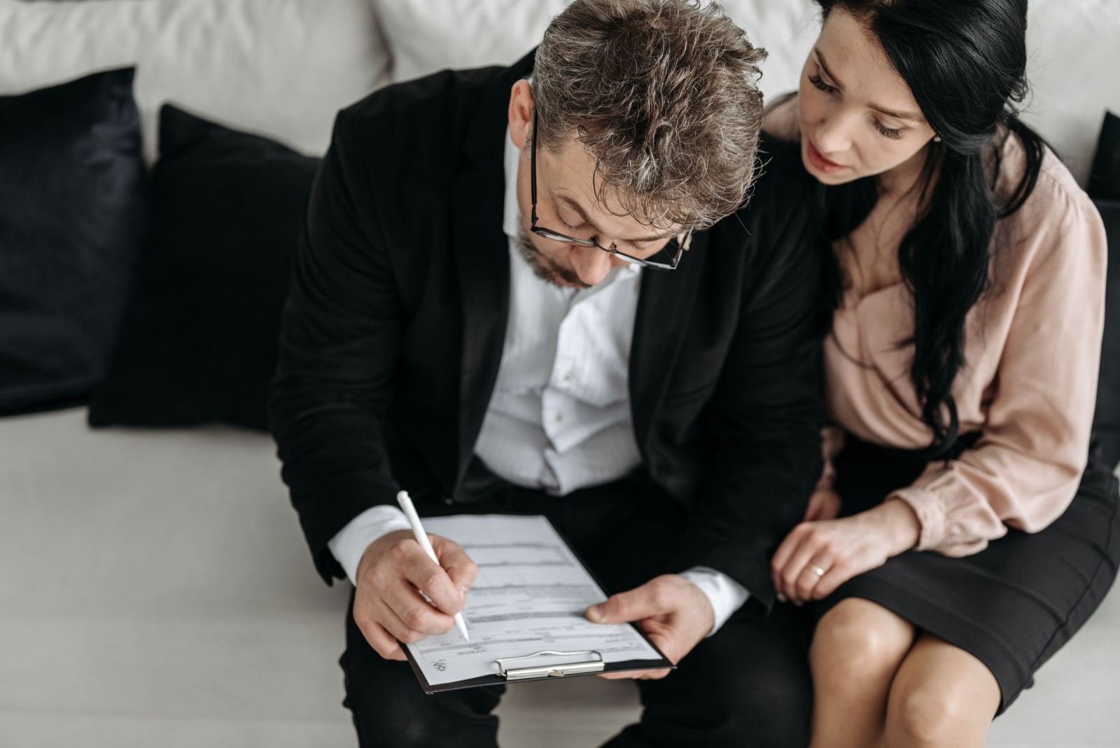 A man and woman look at and fill out paperwork on a clipboard together