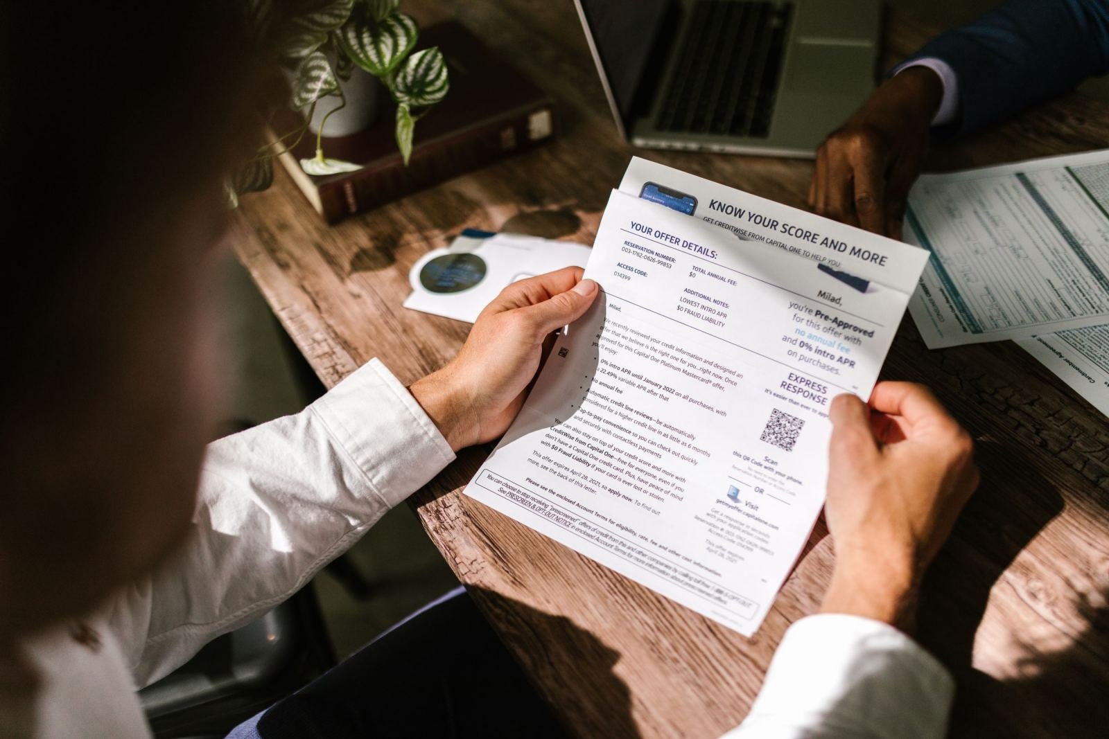 Two people review a printed document together at a wooden table