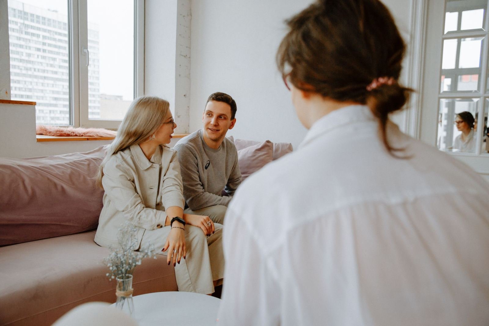 A counselor faces a man and a woman seated on a couch.