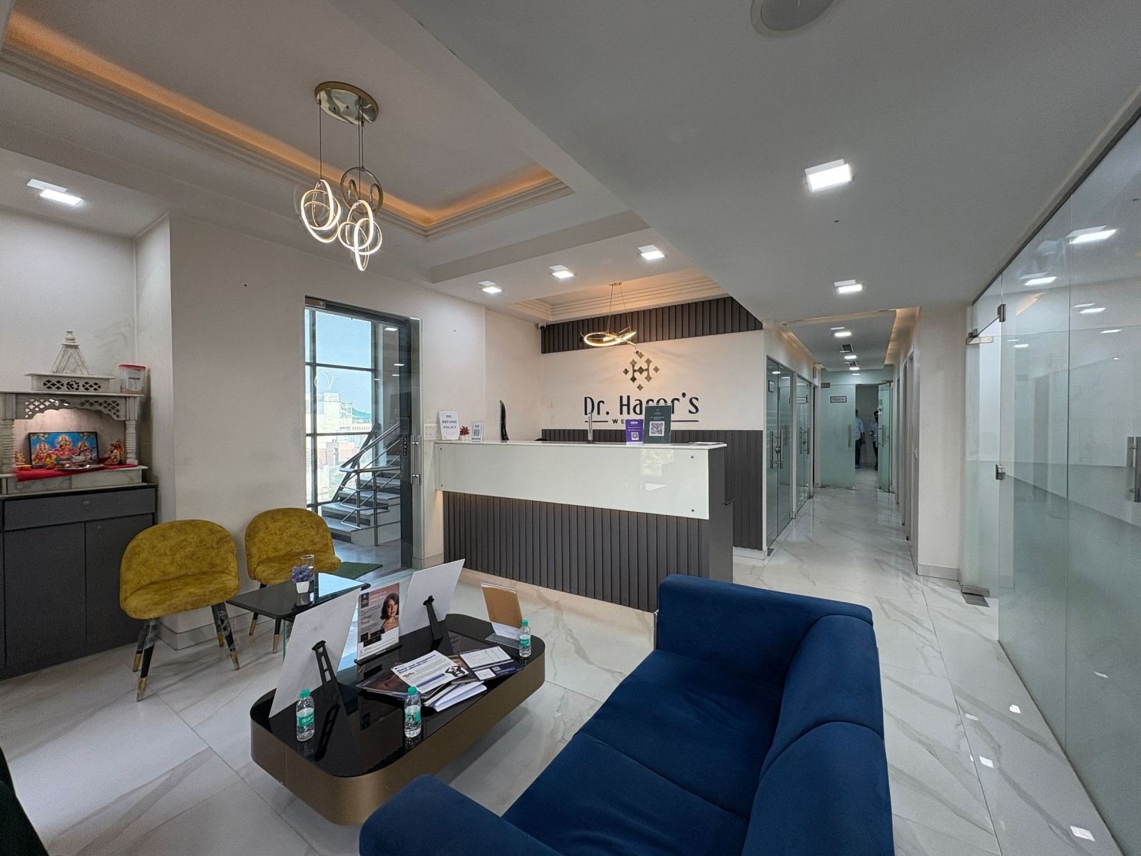 A modern waiting room with a blue sofa, yellow chairs, and a reception desk